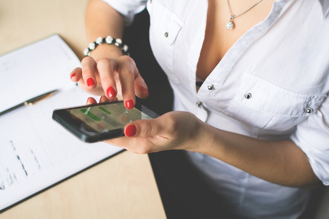 ネイルをした女性がスマホを触る