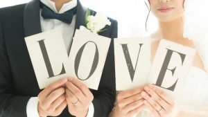 LOVEと書かれた紙を持つ新郎新婦